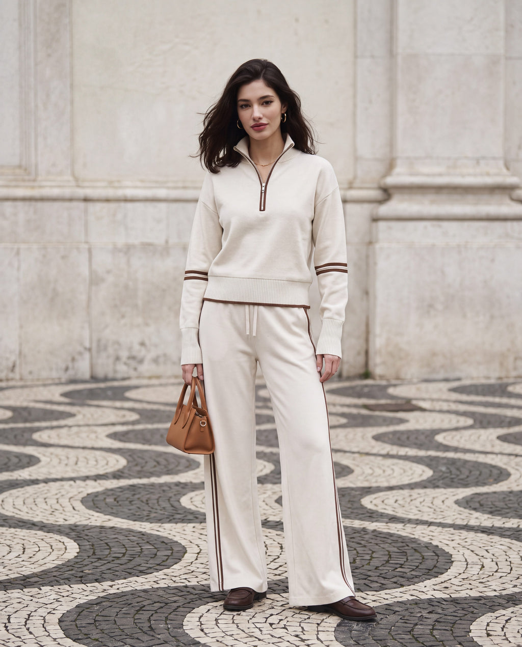 Half-zip knit lounge set in ivory on the wave-patterned paving of Lisbon