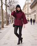 ELARA belted cape in wine red, worn on a Paris street in winter
